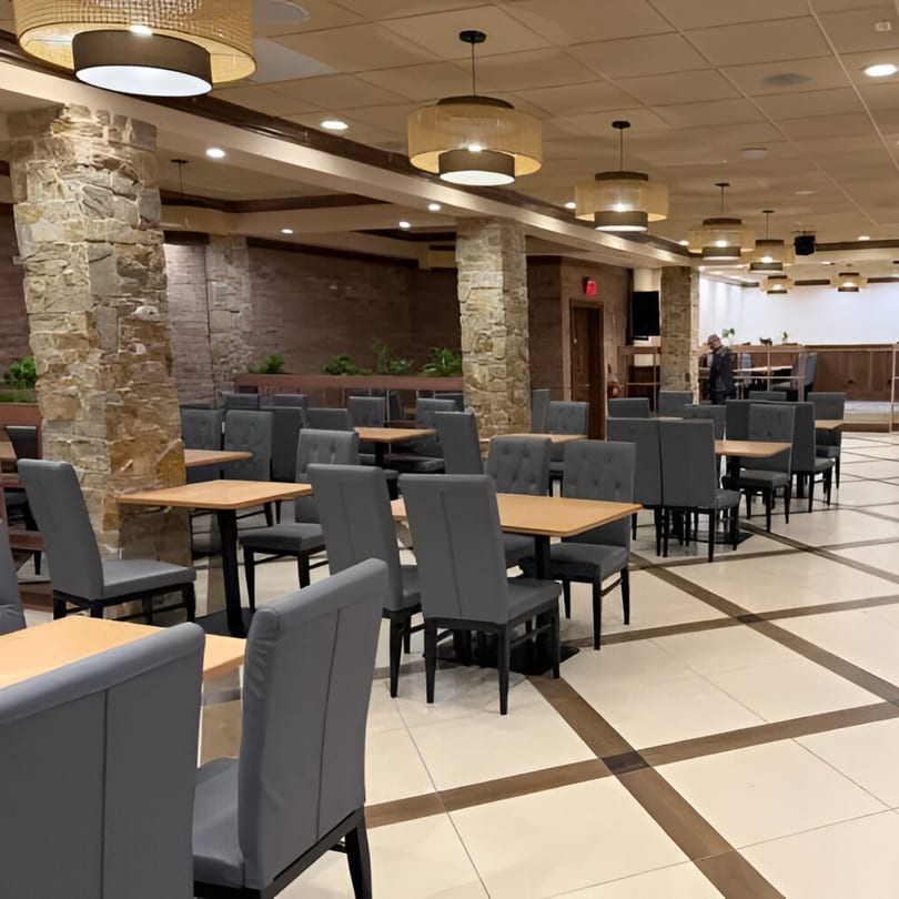 Spacious THAIKULA dining room with gray chairs, light wood tables, stone pillars, and decorative ceiling lights.