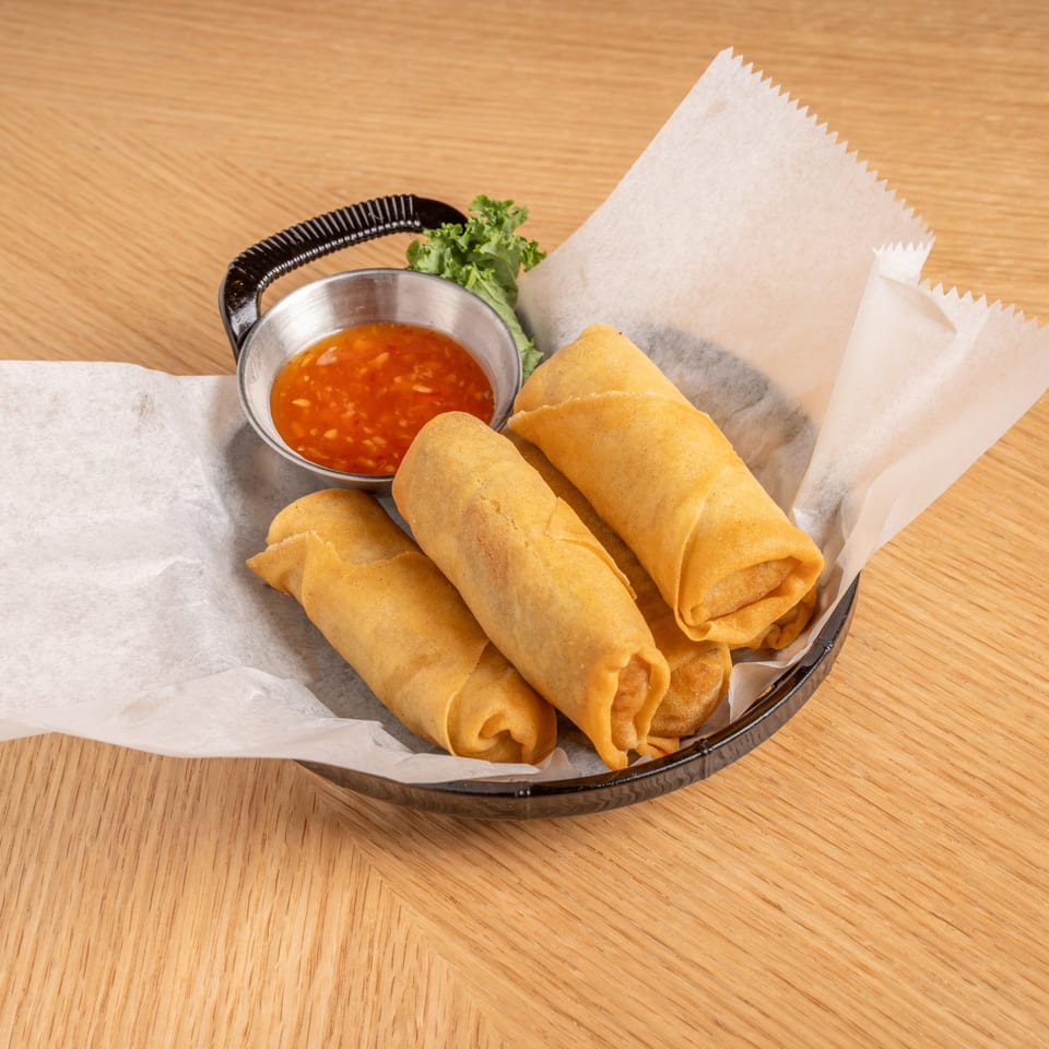 Crispy golden Chinese spring rolls with sweet chili dipping sauce and lettuce in a basket.
